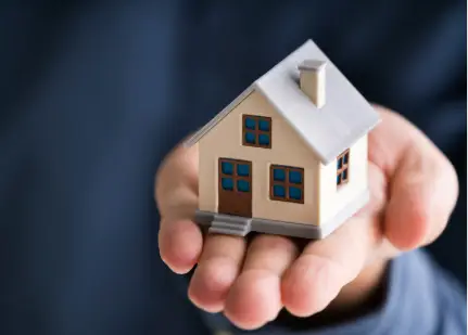 Hand hält Modellhaus symbolisch für Immobilienbewertung