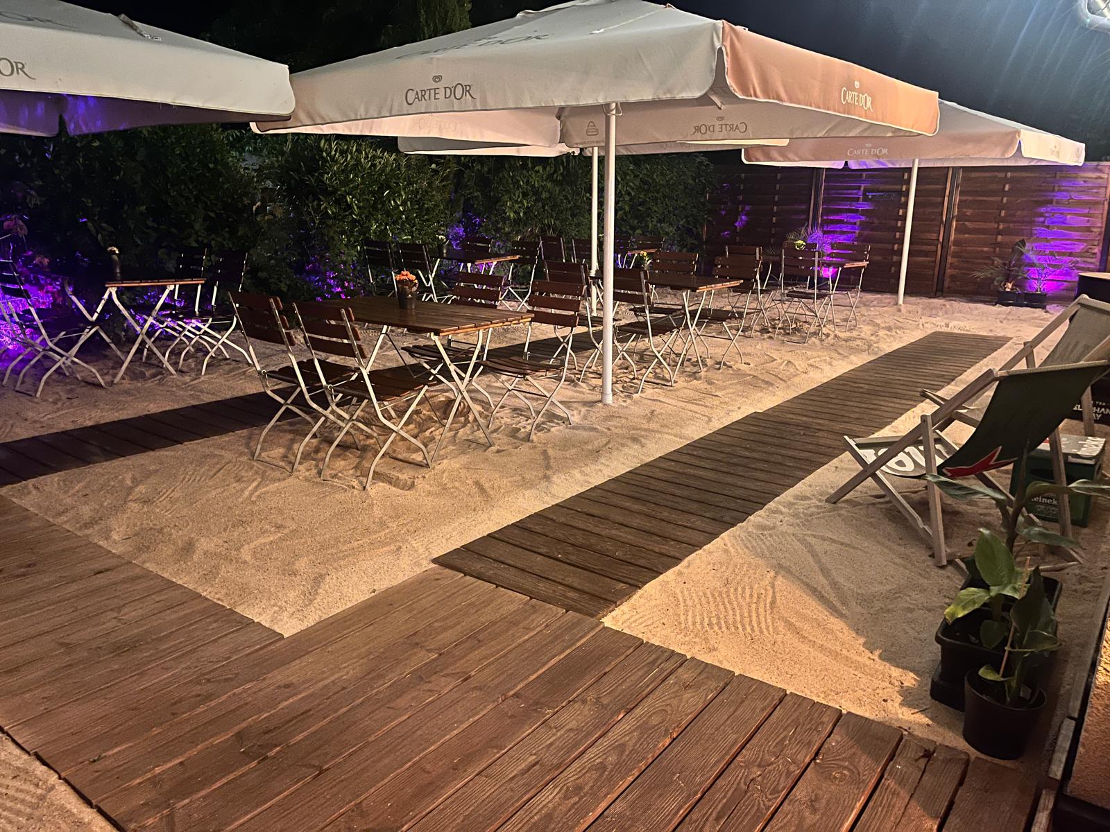 Sandterrasse Cheers! abends mit violettem Licht