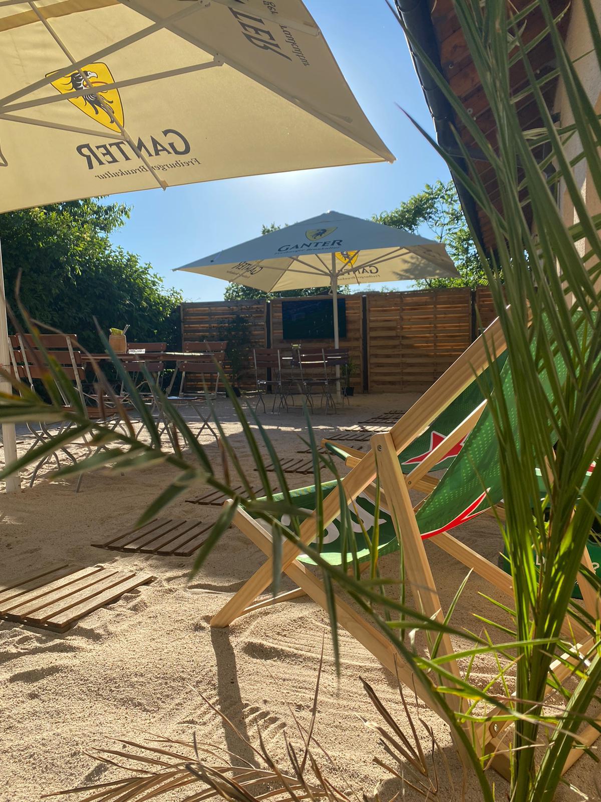 Strandbar Sandterrasse Cheers! tagsüber mit Liegestühlen und Ganter-Schirmen